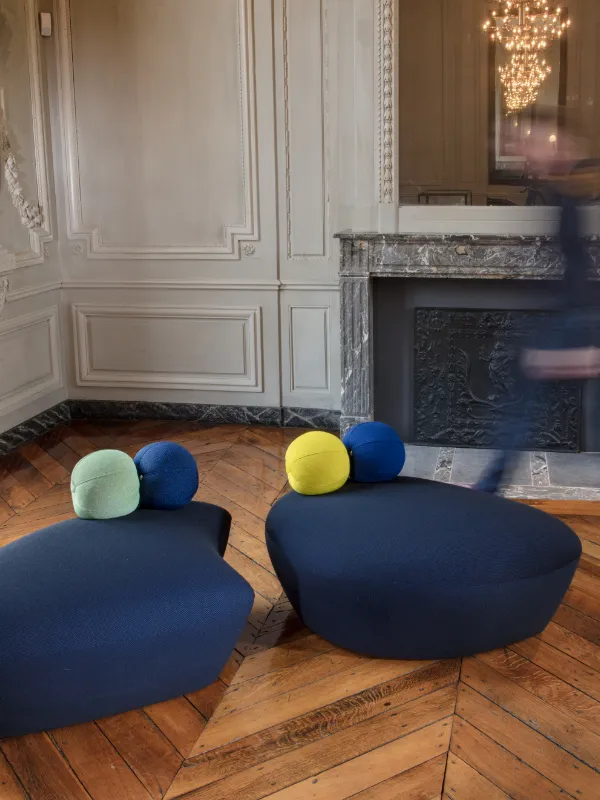 Deux poufs appelés Butterfly créés sur mesure par un tapissier décorateur à Metz en tissus bleu foncé avec des cousins en forme de boule de couleurs
